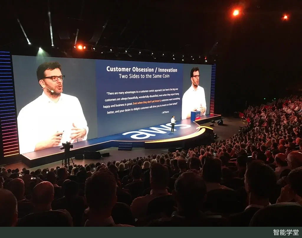 2018 年 AWS Summit 悉尼峰会主会场,演讲者站在印有 aws 标志的舞台上,大屏显示演讲画面,台下坐满观众