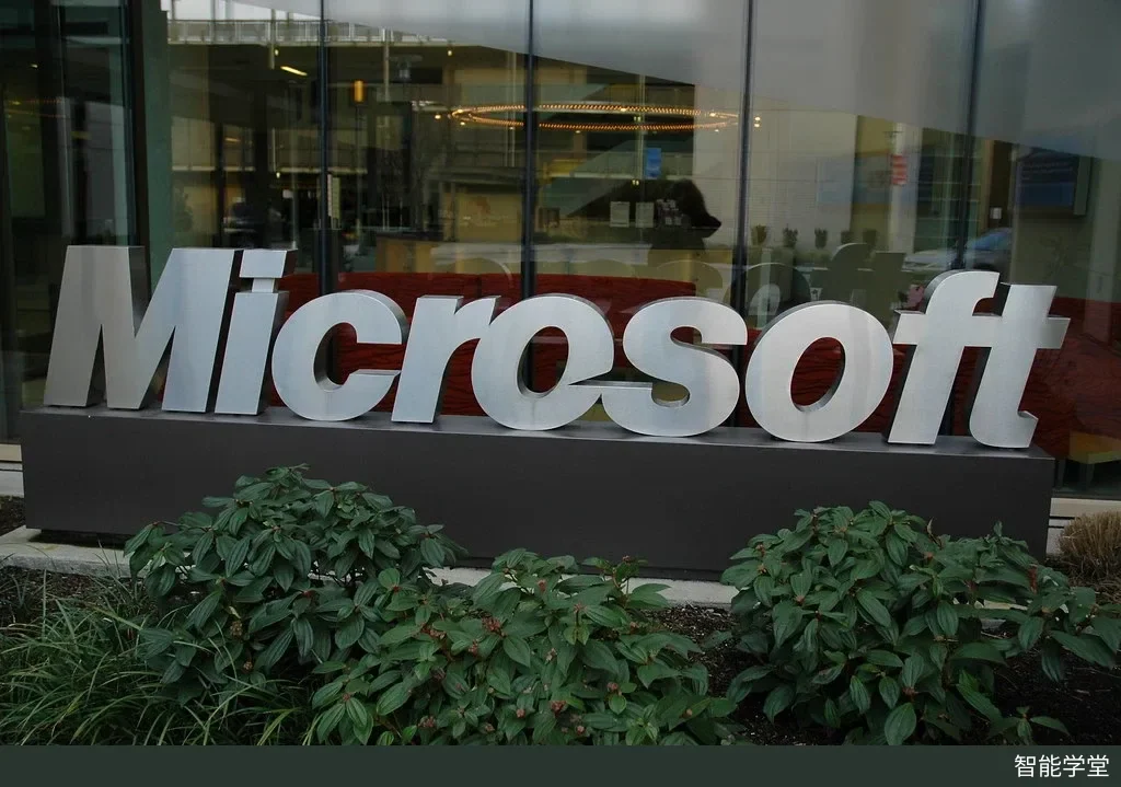 玻璃幕墙建筑前的银色立体 Microsoft 字样标牌,下方种有绿色灌木,摄于雷德蒙德微软园区